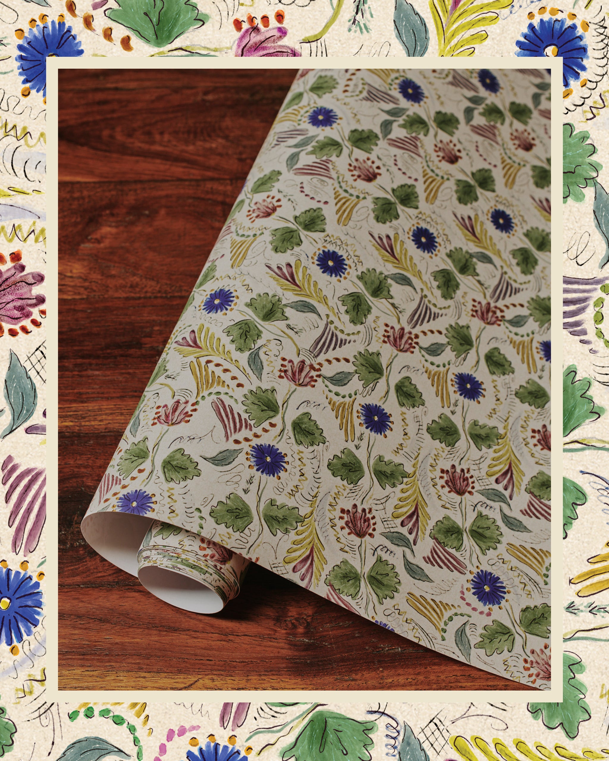 A roll of wallpaper with a floral pattern featuring cornflowers, displayed on a wooden surface.