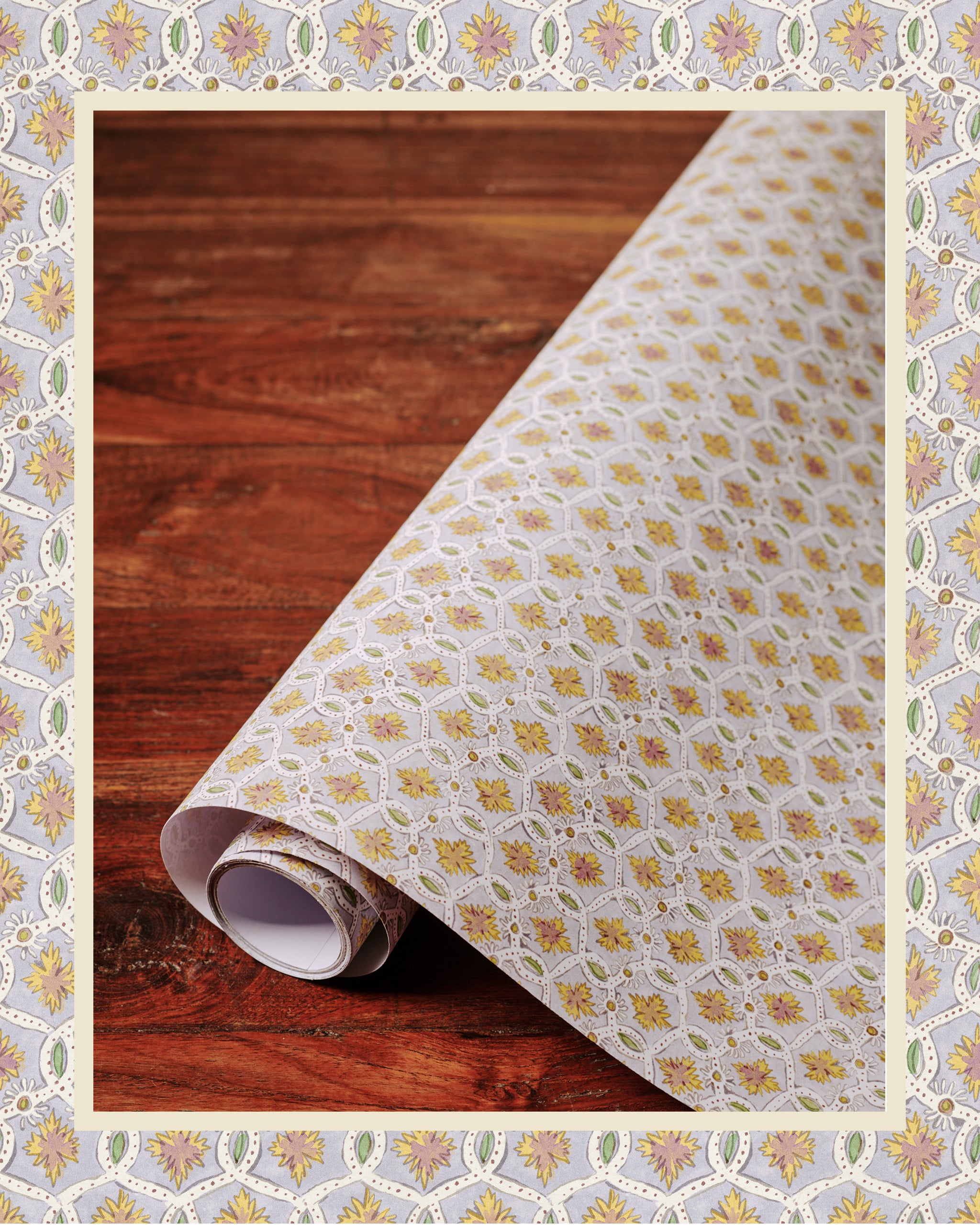 A roll of wallpaper with a floral pattern unrolled enough to show the design, placed on a wooden surface.