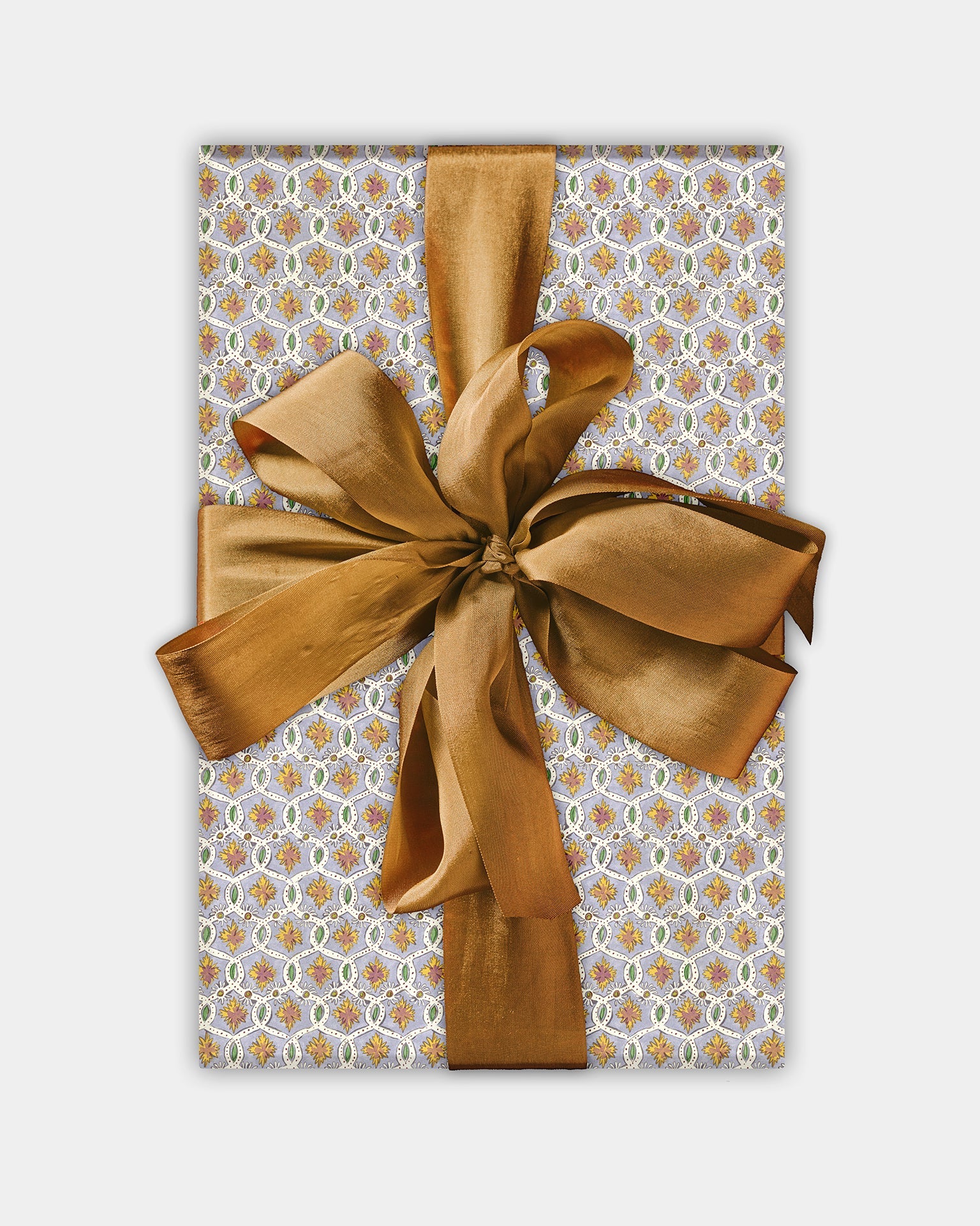 A roll of wrapping paper with a geometric pattern in purple and yellow shades, topped with a bronze ribbon bow.
